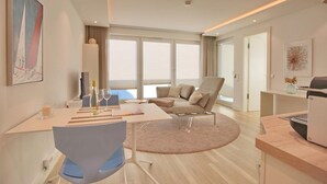 Ett modernt hotellrum med en matplats, en soffa, ett skrivbord och ett stort fönster med utsikt.