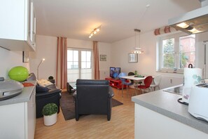 Una cucina moderna con zona pranzo, televisore e finestra con tende.