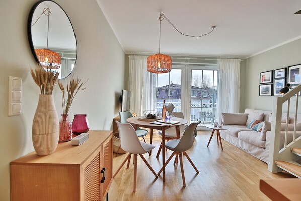 A modern living room with a dining area, large windows, and a staircase.
