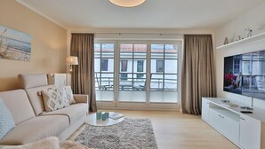 A modern living room with a sofa, coffee table, and TV. - Seerose II Apartment 14 - House Seerose (Scharbeutz)