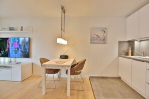 Una cocina moderna con comedor, televisor y un cuadro.