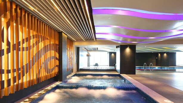A modern spa area with a hot tub, wooden wall panels, and a ceiling with purple lighting. - VS Hotel (Quezon City)