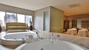 A modern bathroom with a large bathtub, a sofa, and a mirror. - VS Hotel (Quezon City)