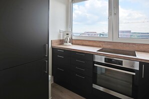 Une cuisine moderne avec des meubles de couleur noire, un lave-vaisselle en acier inoxydable et un four encastré.