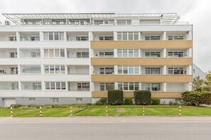 Un edificio residencial de varios pisos con techo plano, varios balcones y entrada con portón.
