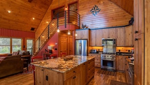 A spacious kitchen with wooden cabinets, a granite island, and a stainless steel refrigerator. - A River Mist Walk - Walk to river, pet friendly, hot tub, pool table (Sugar Grove)