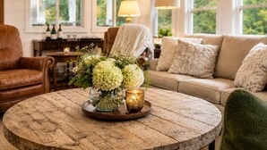 Un salon chaleureux avec une table basse ronde en bois, un canapé et un fauteuil.