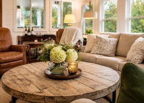 A cozy living room with a round wooden coffee table, a sofa, and a chair.