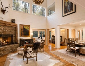 A spacious interior with a stone fireplace, a dining area with a large table and chairs, and a cozy seating area with a fireplace.