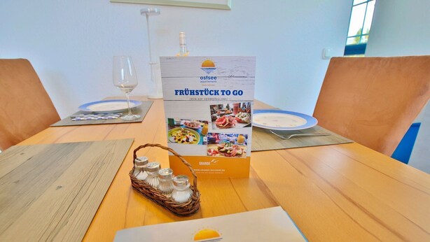 A wooden table with a brochure, salt shakers, and a glass of water.