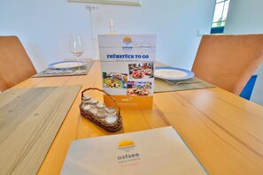 Een houten tafel met een brochure, zoutstrooiers en een glas water.