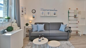 A modern living room with a grey sofa, two round coffee tables, a white cabinet, and a small statue. - Bude 37 Apartment 6 - Bude 37 (Scharbeutz)