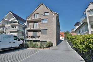 Een modern woongebouw met twee verdiepingen, een bakstenen gevel, balkons en een verharde oprit.