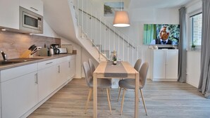 A modern kitchen with a microwave, wooden countertop, and a dining area with a table and chairs. - Bude 37 Apartment 6 - Bude 37 (Scharbeutz)