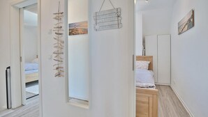 A hallway with a bed, a mirror, and a wall-mounted sign. - Bude 37 Apartment 6 - Bude 37 (Scharbeutz)