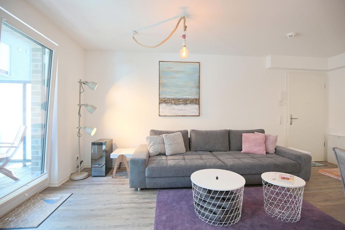 Een moderne woonkamer met een grijze bank, een salontafel en een schilderij aan de muur.