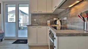Une cuisine moderne avec des meubles blancs, un pare-feu en bois et un four encastré.