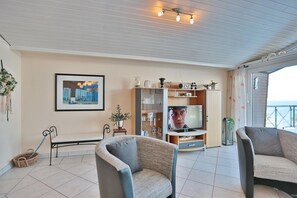 Una sala de estar acogedora con televisor, asientos y una estantería.