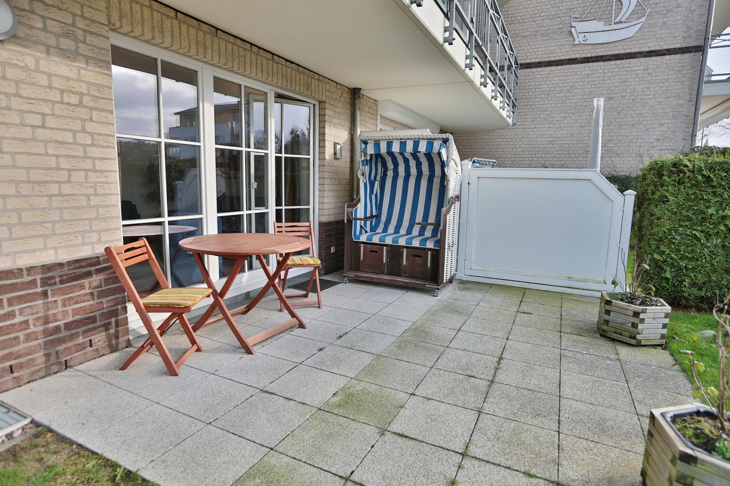 A patio with a table and chairs, a covered seating area, and a small garden with potted plants.