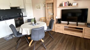 A compact living space with a kitchenette, dining area, and entertainment unit.