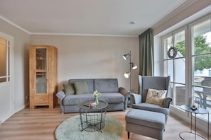 A modern living room with a grey sofa, a grey armchair, a wooden cabinet, and a floor lamp.