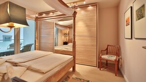 Un dormitorio con cama con dosel, una silla y obras de arte en las paredes.