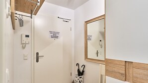 Ein Hotelzimmer mit weißer Tür, einem Nachttisch, einem Spiegel, einem Kleiderständer und einem auf Deutsch schild.
