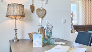 Ein Holztisch mit einer Lampe, einem Schild, einem dekorativen Herz, einer Glasvase und einer Broschüre.