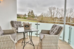 A balcony with wicker furniture, a table, and a basket labeled "GREEN GARDEN". - Dünenhaus 3 Appartement 7 - Dünenhaus (Scharbeutz)