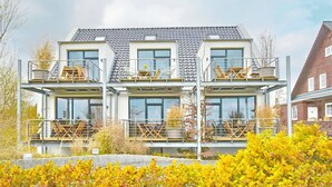 A modern multi-story house with balconies, large windows, and a tiled roof.