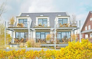 Una casa moderna de varios pisos con balcones, ventanas amplias y techo de tejas.