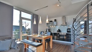 A modern kitchen with a dining area, large windows, and a spiral staircase.