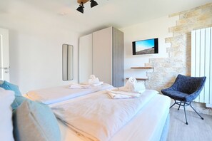 Ein Hotelzimmer mit Bett, Sessel, Fernseher und einer Steinwand.