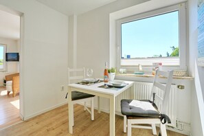 Ein Essbereich mit einem Tisch für zwei Personen, einem Fenster mit Blick und einer weißen Heizkörper.