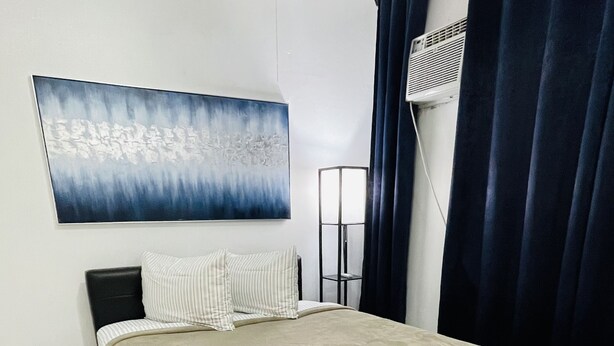A neatly arranged bedroom with a bed, a wall-mounted air conditioner, and a floor lamp. - 5** Start New Beautiful Aparment w/ 2 Bedrooms. (San Juan)