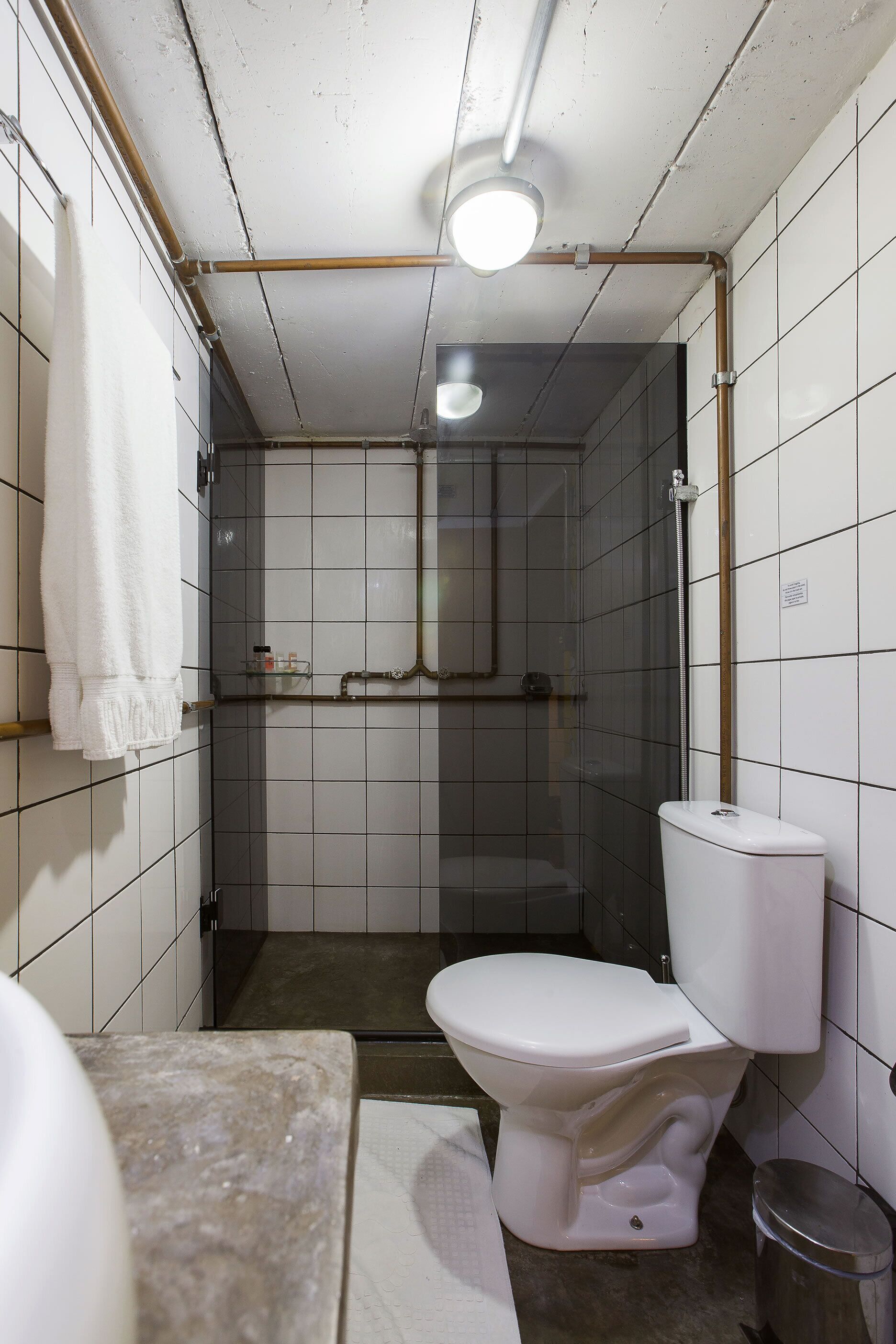 Une salle de bain comprenant des toilettes, un lavabo, un miroir et un espace douche.