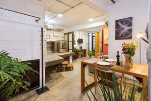 A modern kitchen with a large island, a dining area with a wooden table, and a view of the kitchen in the background. - VILA MADALENA: BEST Location - Artistic Apartment (São Paulo)
