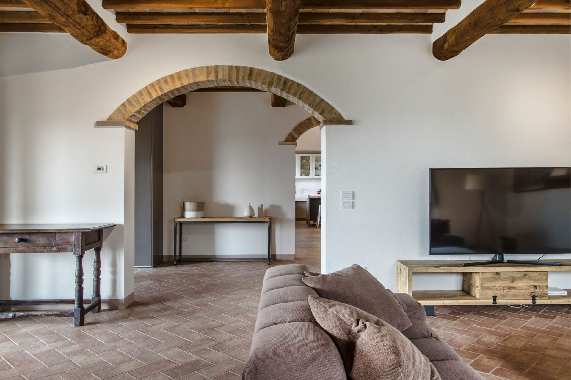 A living room with a stone fireplace, a wooden table, a sofa, and a TV.