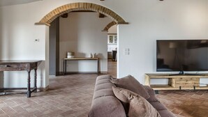 A living room with a stone fireplace, a wooden table, a sofa, and a TV.