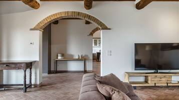 A living room with a stone fireplace, a wooden table, a sofa, and a TV.