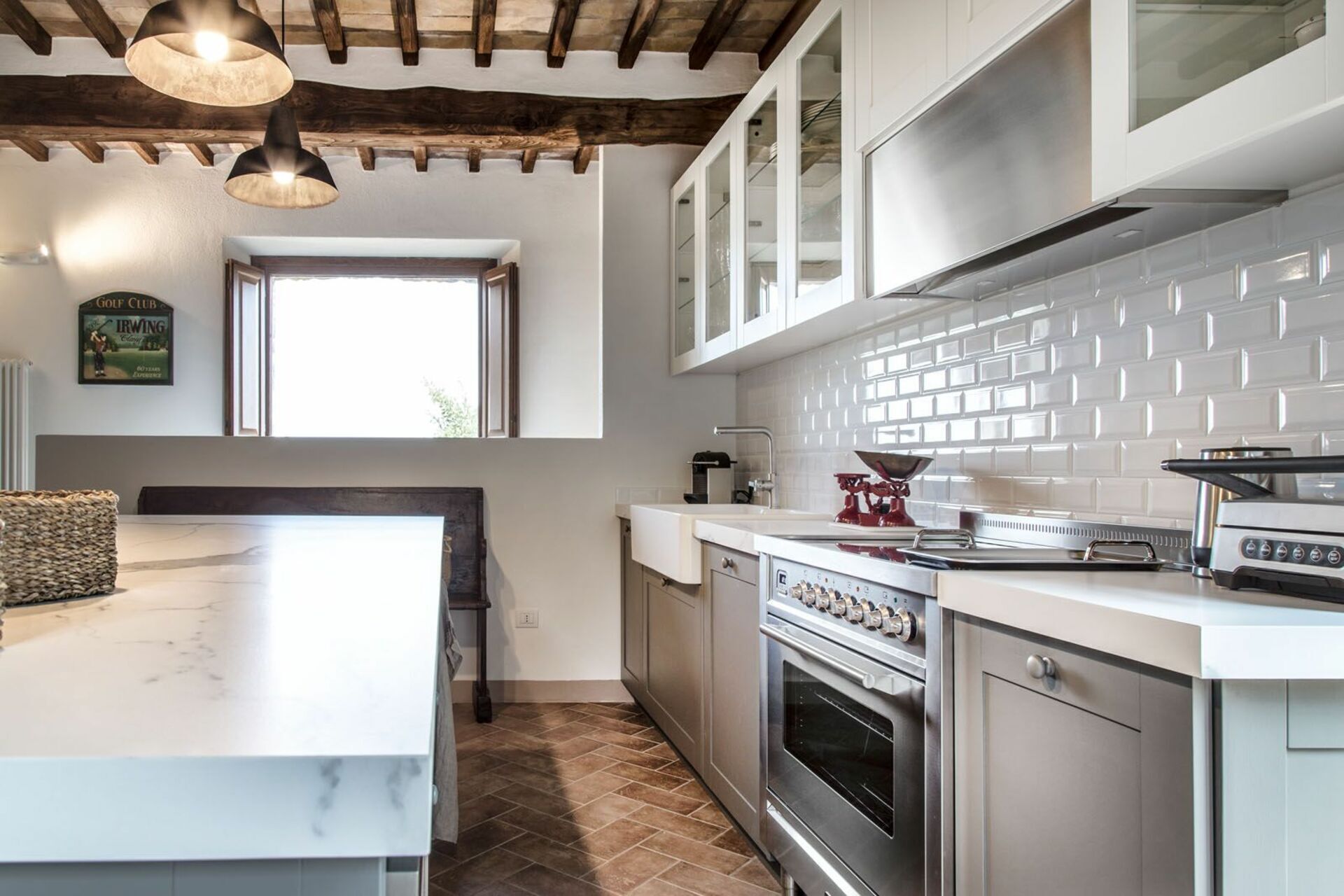 A modern kitchen with white cabinets, a built-in oven, and a large window.