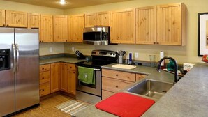 A modern kitchen with wooden cabinets, stainless steel appliances, and a granite countertop. - Cozy Cabin Retreat,  Enjoy the outdoors, Pets Welcome! (Eureka)
