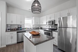 Enjoy cooking in this well-equipped kitchen with a central island, refrigerator, microwave, and oven.