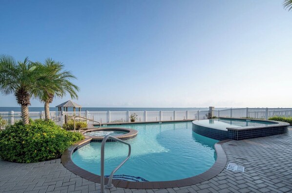 Relax by the serene pool surrounded by lush greenery and palm trees.