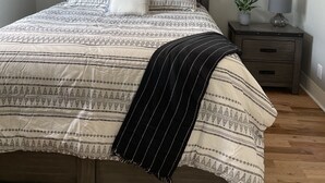 A bedroom with a bed, a nightstand, a ceiling fan, and a window.