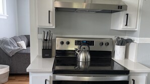 A modern kitchen with white cabinetry, a stainless steel stove, and an oven.