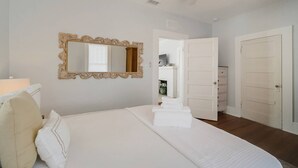Ein Schlafzimmer mit einem Bett, einem Deckenventilator, einem Spiegel und einer Tür zu einem anderen Raum.