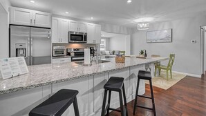 A modern kitchen with stainless steel appliances, a granite countertop, and bar stools.