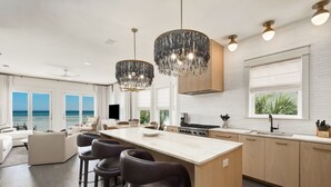 Une cuisine moderne dotée d’un îlot central, de tabourets de bar et de luminaires suspendus.