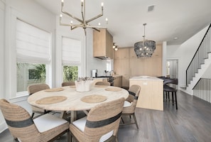 A modern kitchen with a round dining table, wicker chairs, and a central island. - Shellstone Cottage | Forever Gulf Views, Private Heated Pool, Beach Walkover + Close to Alys (Inlet Beach)